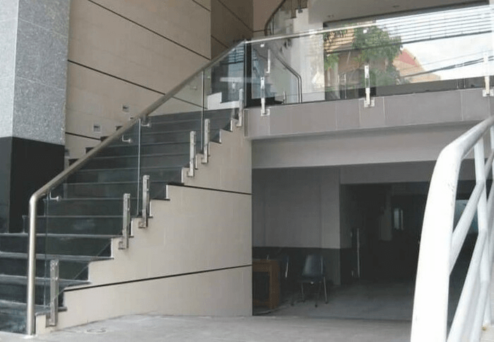 Cầu thang inox kính cường lực sảnh trước tòa nhà văn phòng.